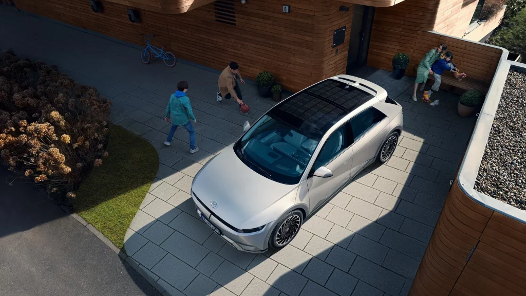 IONIQ 5 med solcellstak på uppfart med lekande barn