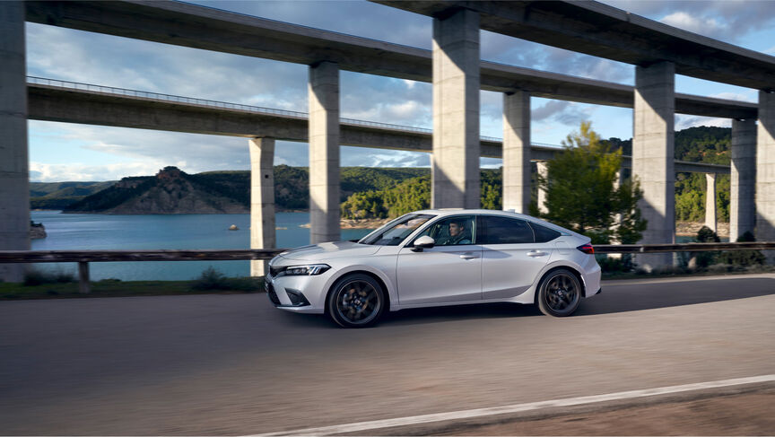 Honda Civic Advance i pärlemovit kör på bro med vatten i bakgrunden