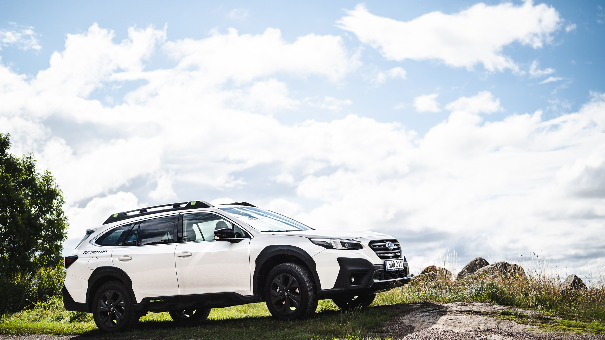 Vit Subaru Outback med RA Motor dekaler som parkerat bland stenar