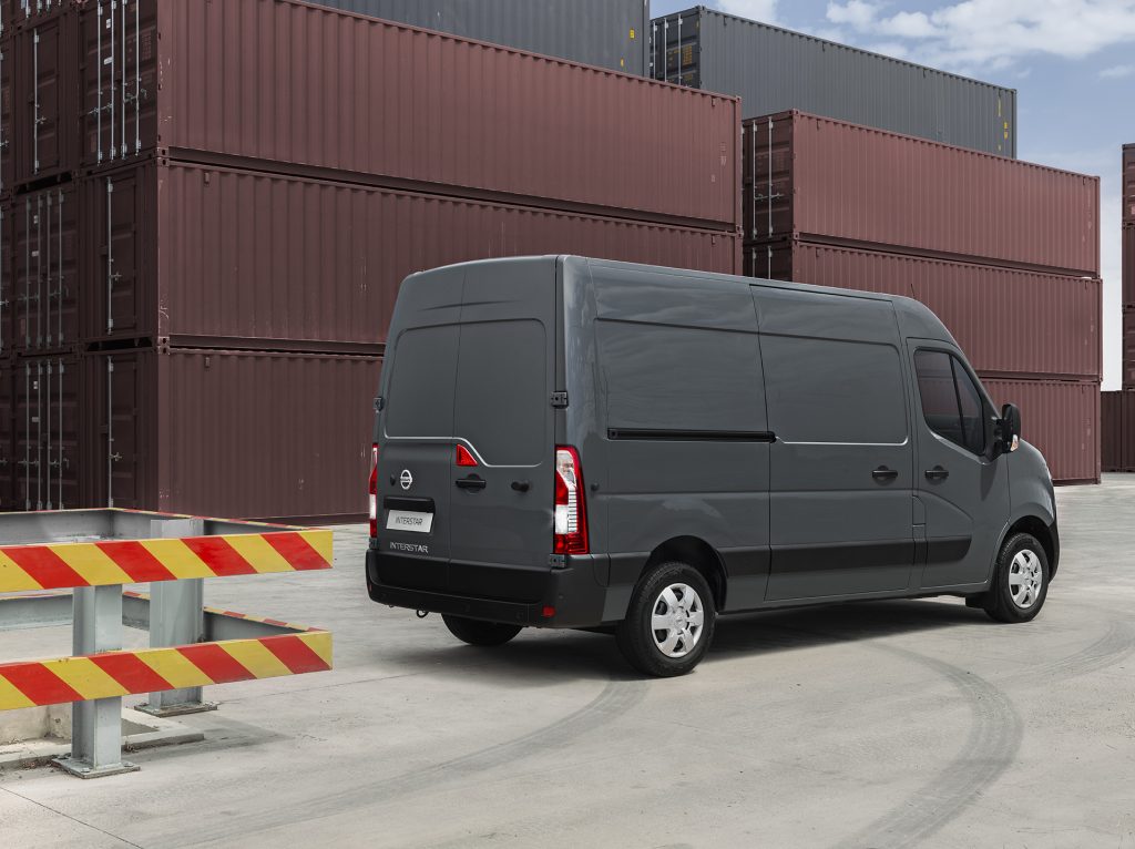 Grå Nissan Interstar parkerad vid containrar