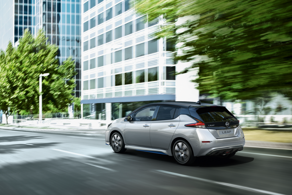 Nissan Leaf kör i stadsmiljö med träd i bakgrunden