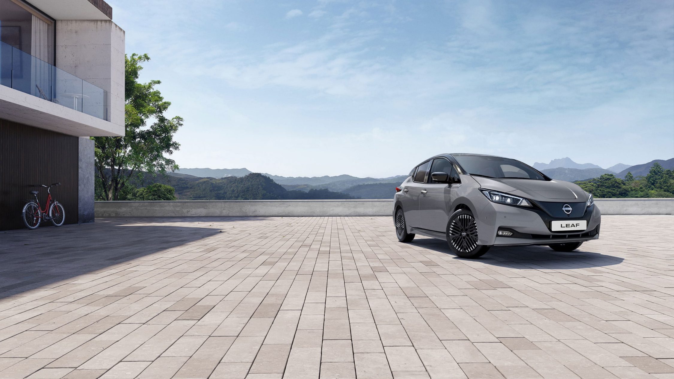 Grå Nissan Leaf med svart tak på villauppfart