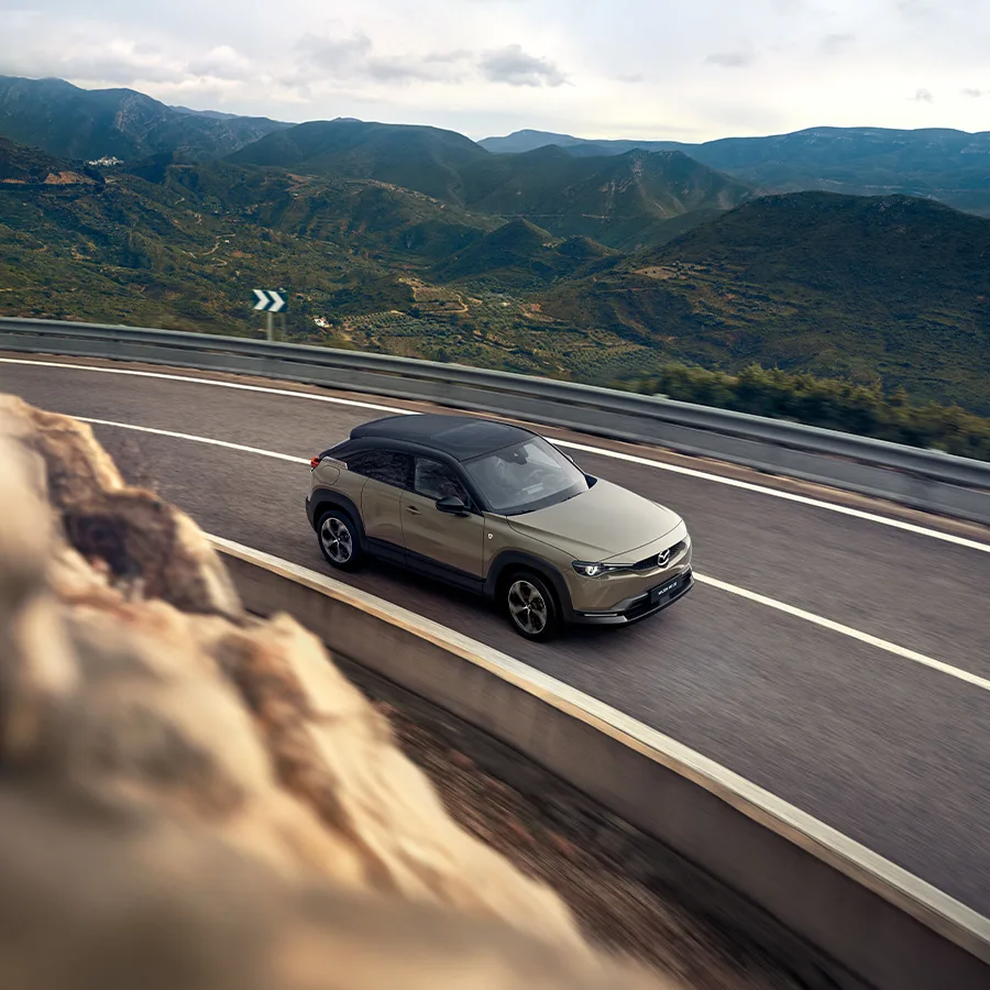 Mazda MX-30 R-EV Makoto som kör längs en väg i bergen
