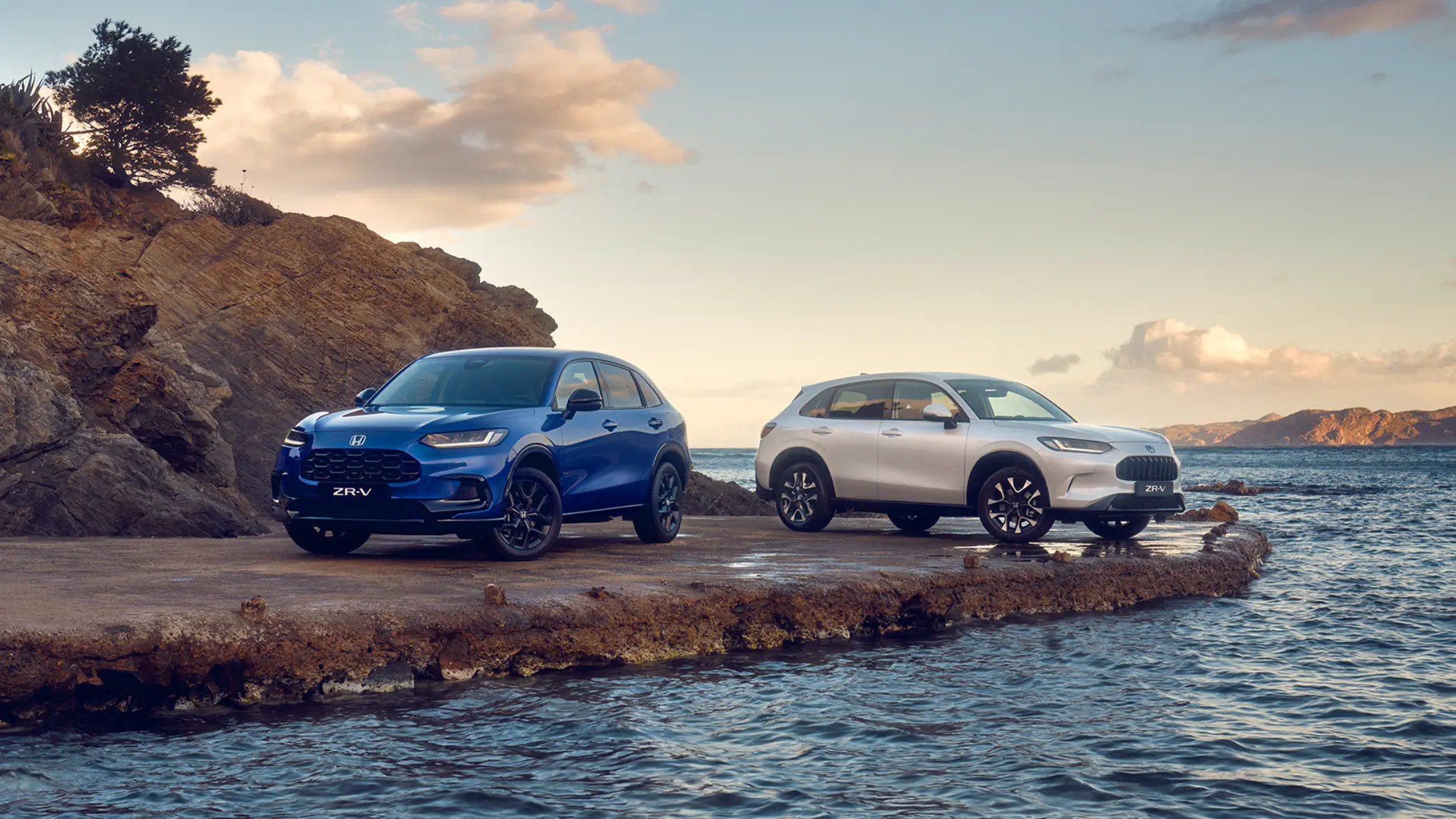 Två Honda ZR-V parkerade vid havet - en blå och en vit