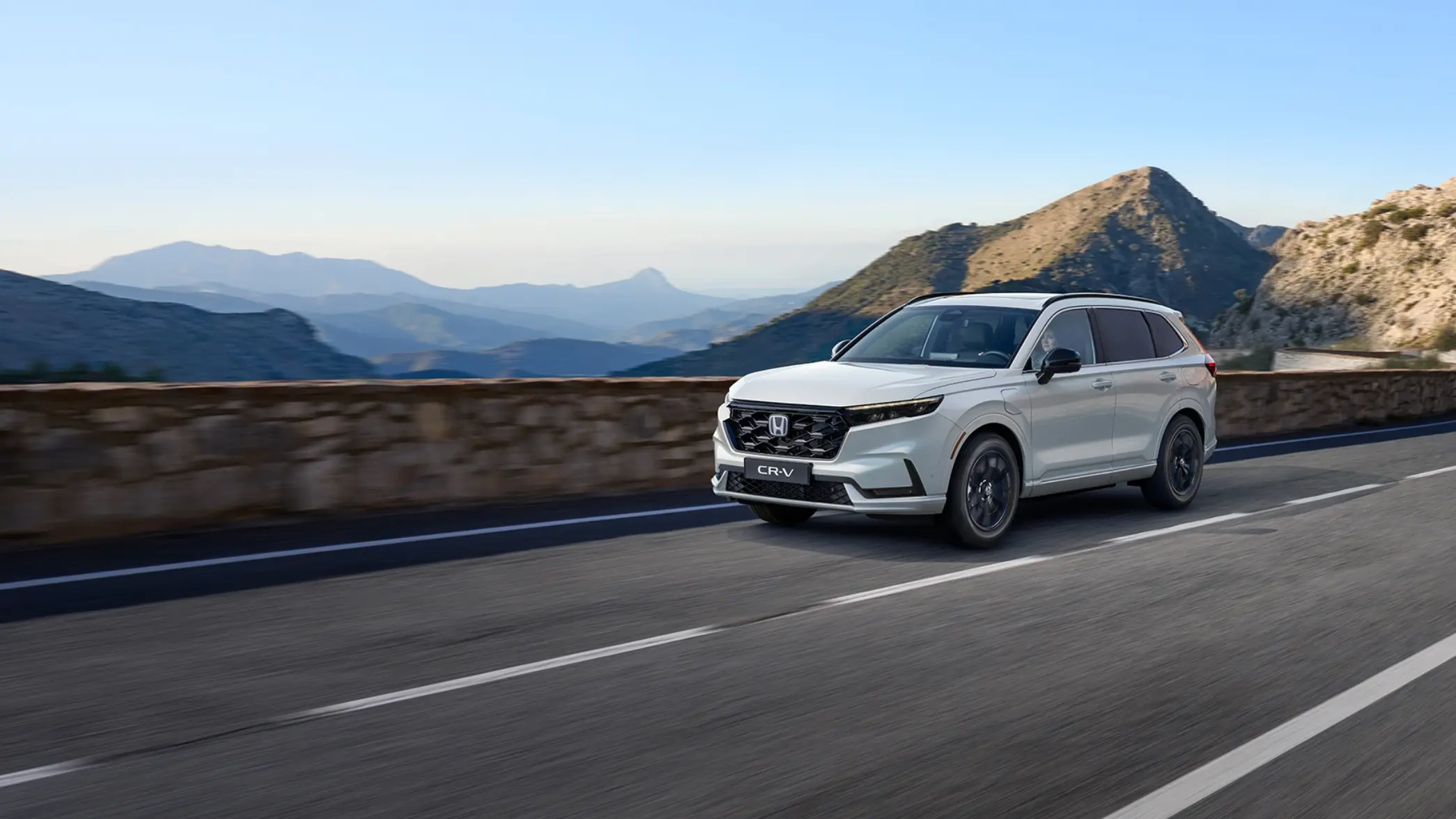 Honda CR-V Plug-in Hybrid Vit kör längs en väg bland berg