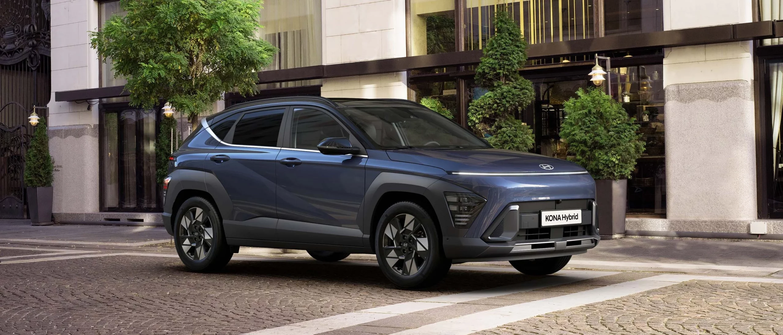 KONA Hybrid i färgen Denim Blue står parkerad längs med en gågata