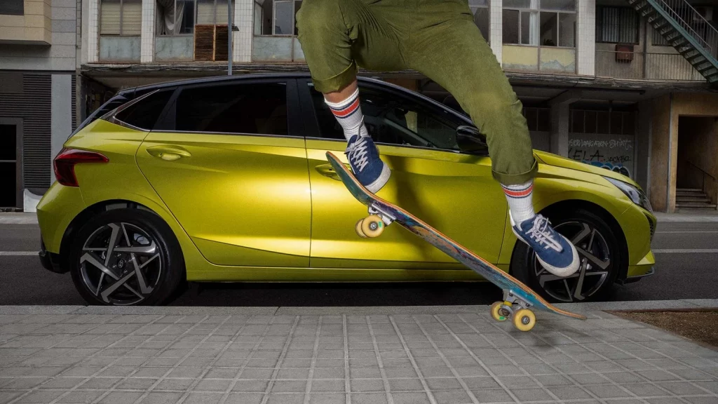 Kille med skateboard hoppar framför en Hyundai i20 i färgen Lucid Lime