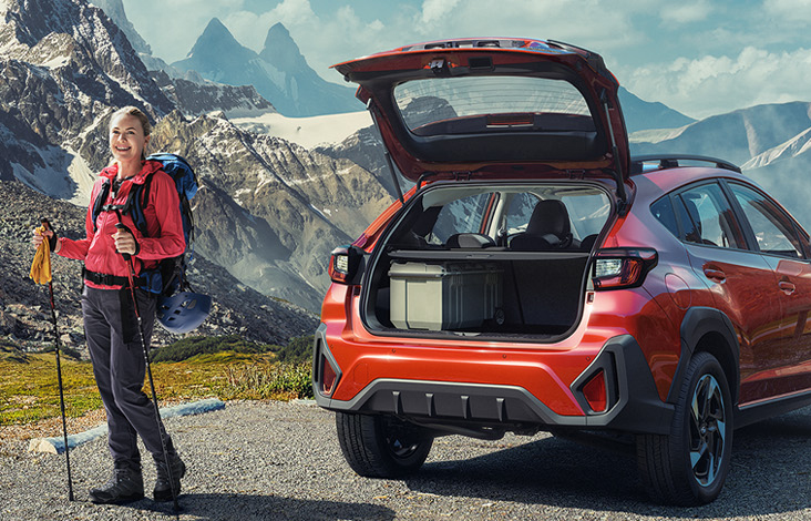 Vandringklädd kvinna står bredvid röd Crosstrek