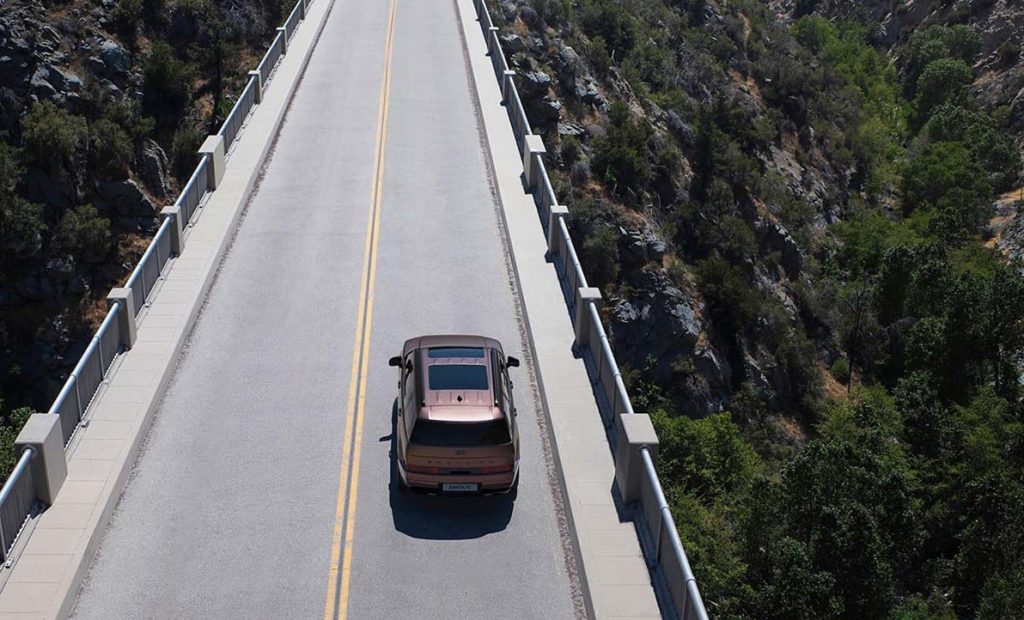 Helt nya SANTA FE Plug-in Hybrid i kopparfärg drönarbild ovanifrån körandes på en bro