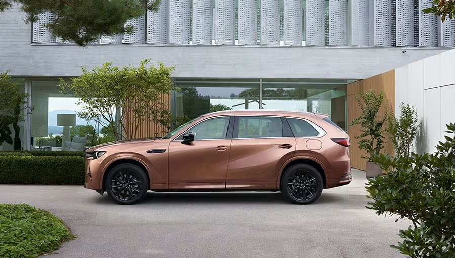Mazda CX-80 Diesel i nya färgen Melting Copper parkerad utanför ett modernt hus