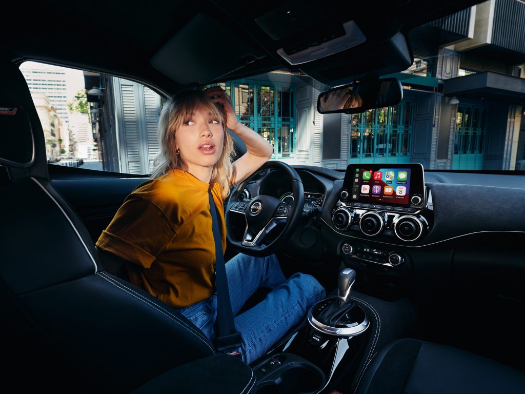 Nissan Juke Interiörbild - tjej med orange t-shirt sitter vid förarplatsen